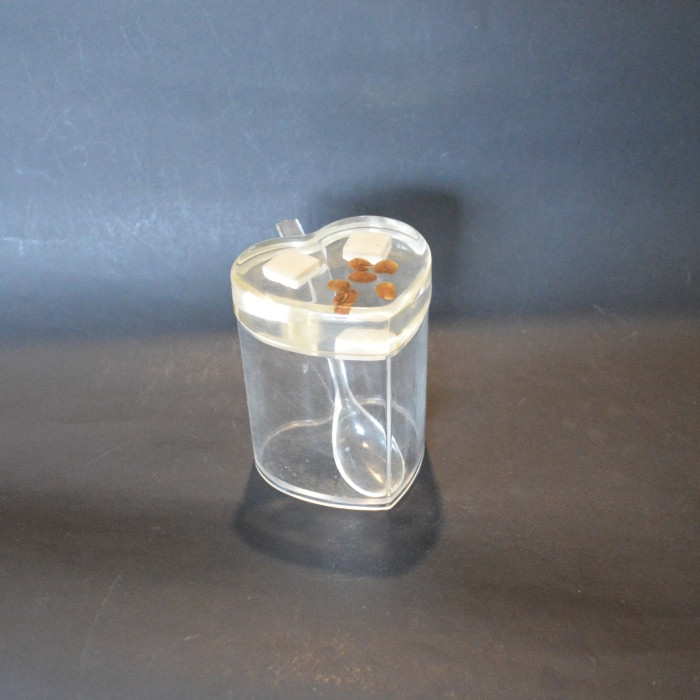 Une boite avec sa cuillère en matière acrylique plexiglas translucide.